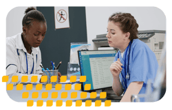 Two healthcare workers coordinating patient schedules at the front desk