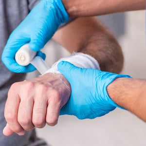 A healthcare professional bandages a patient's wrist.
